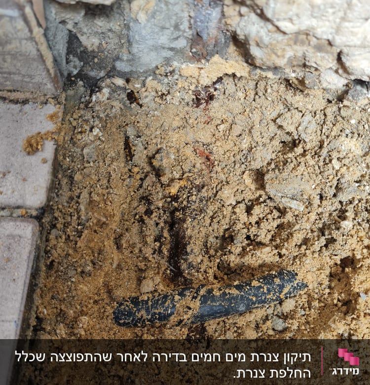 צינור שחור שבור בתוך אדמה וחול